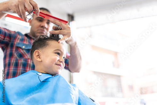 Cute Boy Getting a Hair Cut in a Barber Shop. Beauty Concept.