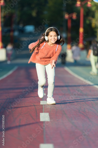 Playlist for active day. Girl cute with headphones. Little child enjoy activity. Kid walking running in park listening music. Music fills me with energy. Enjoy walk with favorite music in headphones