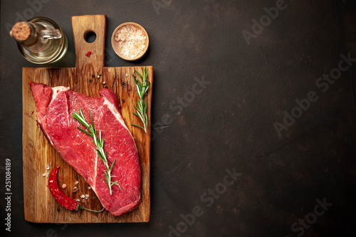 raw new york steak with ingredients on a cutting board. on the background of dark stone.with copy space