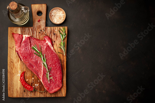 raw new york steak with ingredients on a cutting board. on the background of dark stone.with copy space