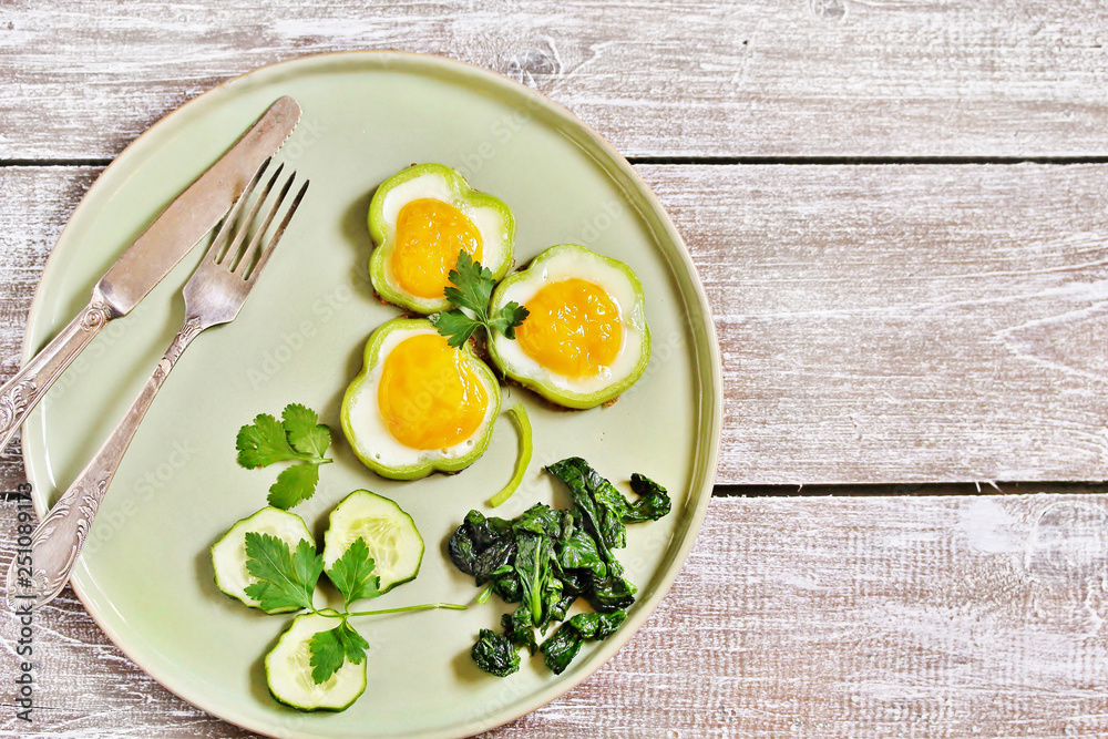 green breakfast on St. Patrick's Day. eggs in the form of clover. Fried Eggs Shamrock in Green Pepper rings with Braised Spinach. parsley leaves like clover leaves. green breakfast on St. Patrick's Day. eggs in the form of clover. Fried Eggs Shamrock in Green Pepper rings with Braised Spinach. parsley leaves like clover leaves.