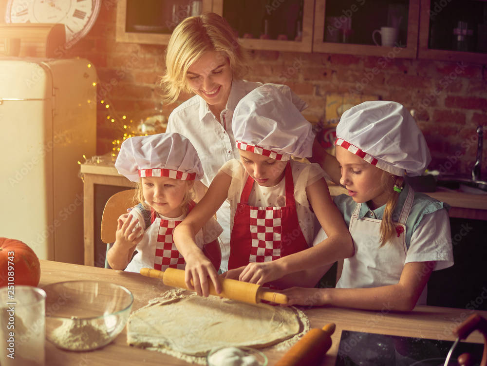 Cheerful mother with daughters cooking in kitchen at home all together. Active leisure and lifestyle concept Cheerful mother with daughters cooking in kitchen at home all together. Active leisure and lifestyle concept