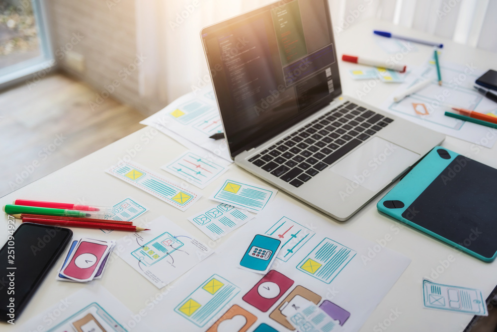 Working desk of programmer developing technologies mobile phone with sketch application on table. User experience concept. Working desk of programmer developing technologies mobile phone with sketch application on table. User experience concept.