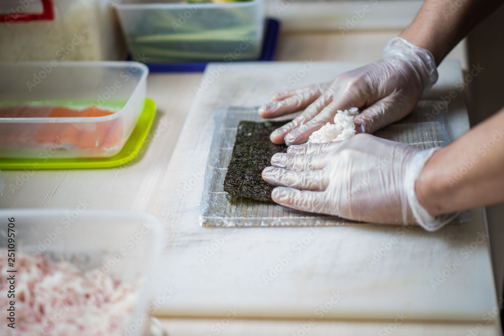 Cook hands making japanese sushi roll. Japanese chef at work preparing delicious sushi roll with eel and avocado. Appetizing japanese food. Cook hands making japanese sushi roll. Japanese chef at work preparing delicious sushi roll with eel and avocado. Appetizing japanese food.