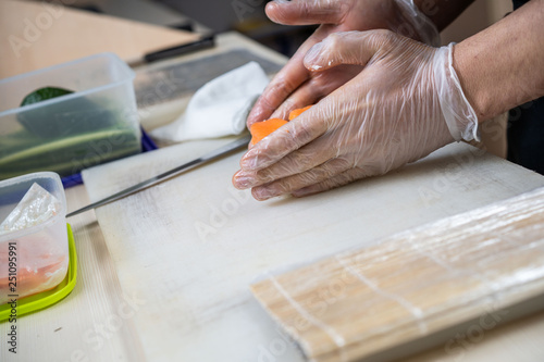 Cook hands making japanese sushi roll. Japanese chef at work preparing delicious sushi roll with eel and avocado. Appetizing japanese food.