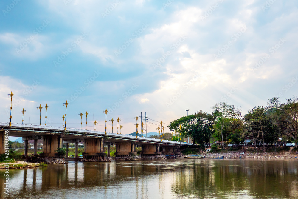 Naklejka premium The bridge at the grand river in Chiang Rai province in Thailand with the blue sky and white cloud background. 