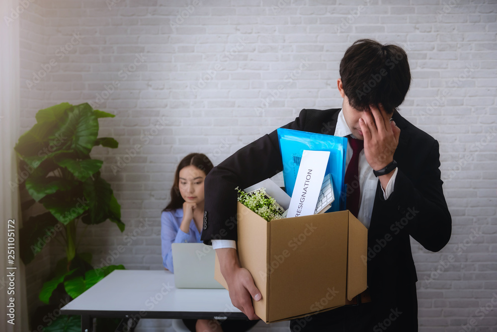 Φωτογραφία Business man stressed after resignation or be fired  from business company with holding cardboard box packing her belonging and boss on background
