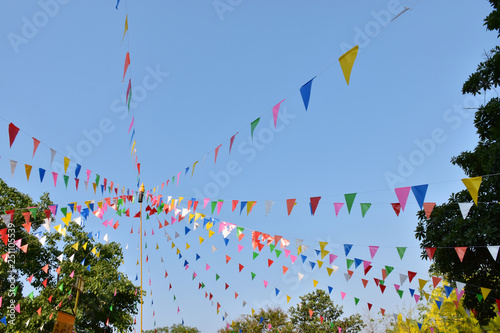 Colorful triangle flags fasten in line with pole in the temple ,  these are decorations in Song kran festival in Thailand.
