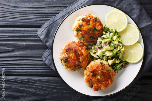 Delicious healthy salmon fritters with avocado salsa and lime closeup on a plate. horizontal top view photo