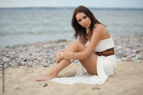 Gorgeous dark-haired girl in dress on sandy beach