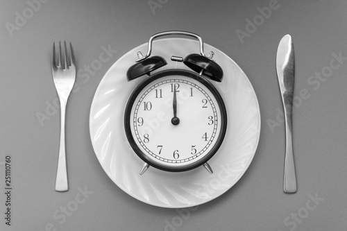 Alarm clock with fork and knife on the table. Time to eat, Breakfast, Lunch time and dinner concept. Black and White Concept