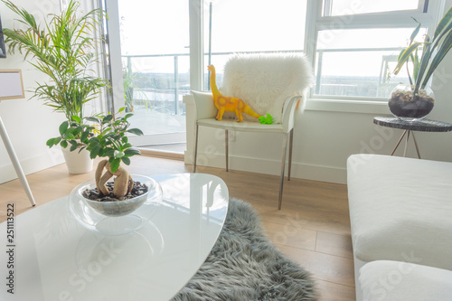 Real family living room with toy dinosaurs on a chair, depicting parenting lifestyle and a home with kids, with white furniture photo