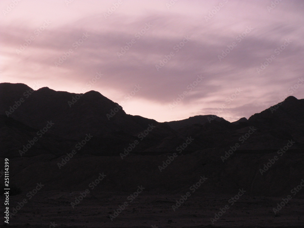 Desierto de Dahab, montañas de Egipto en la noche fotos contra del sol y nubes moradas violetas