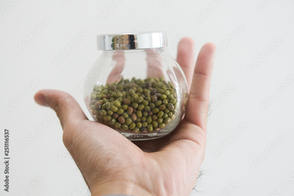 Male hand holding a jar of spice on white background