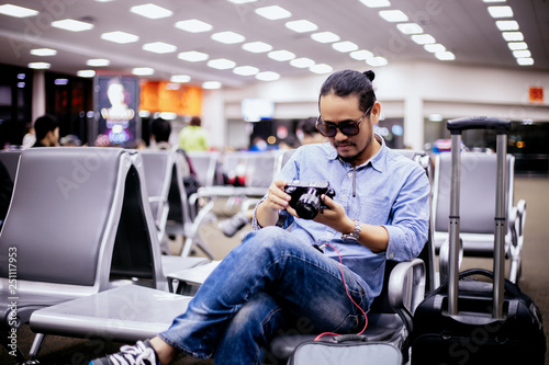 Asian man with backpack  traveler checking picture on camera at an airport © tuiphotoengineer