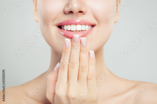 Natural beauty concept. Closeup female smile with natural pink lips and french manicure hand