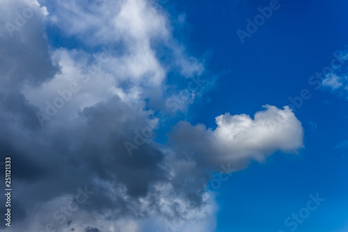 Fluffy white and grey clouds against a bright, colorful blue sky