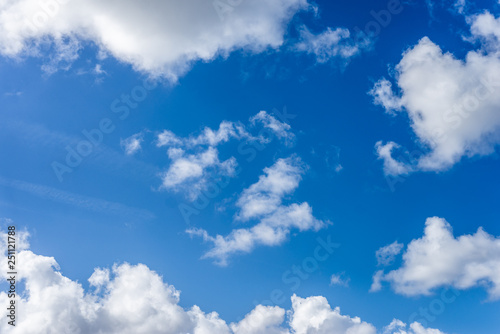 Fluffy white clouds against a bright, colorful blue sky