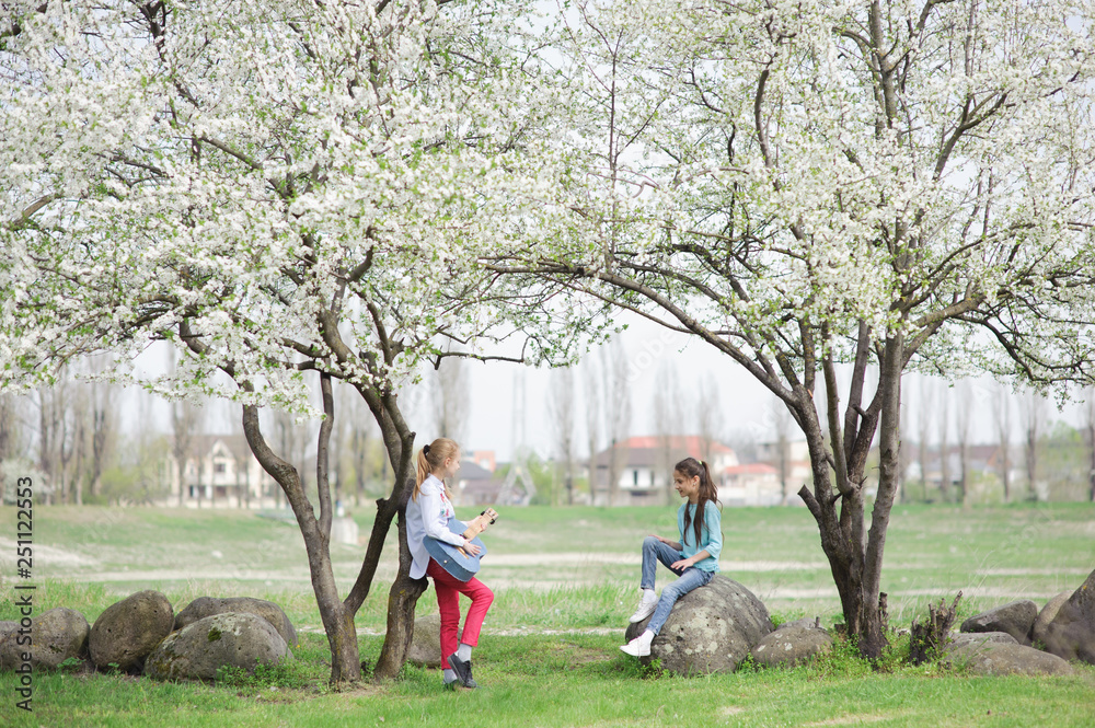 two little happy girls playing guitar and singing songs together in spring outdoor park