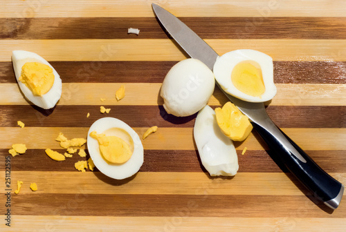 Chopped boiled eggs laid on a wooden cutting board next to a kitchen knife. Top view. photo