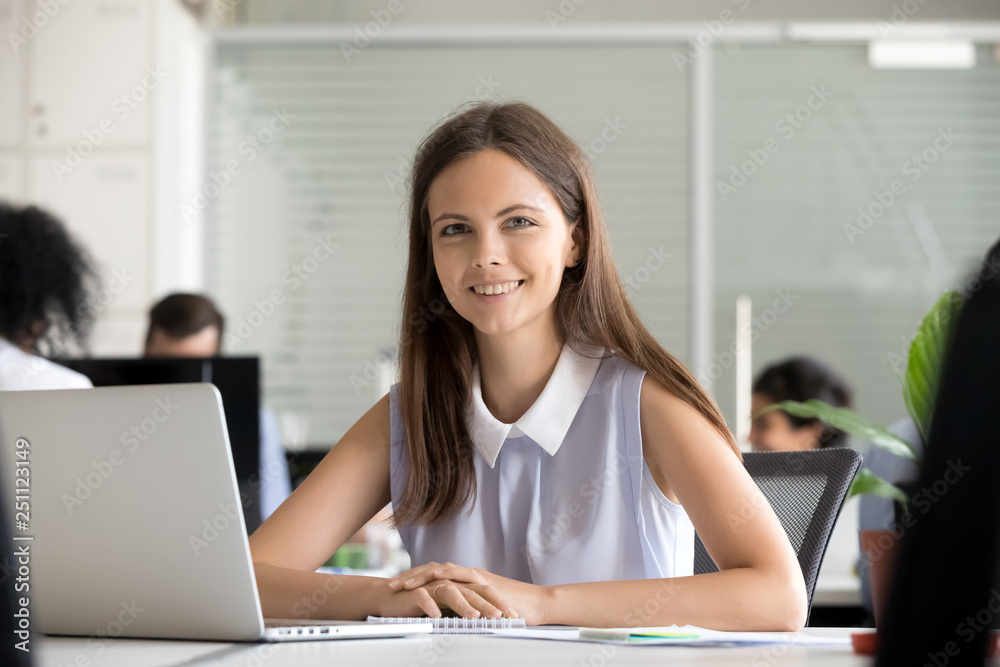 Fototapeta premium Headshot young employee sitting in office looking at camera