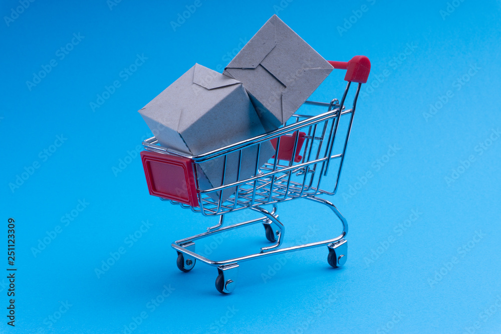 Shopping cart and box on blue background, business and shopping concept. Selective focus Shopping cart and box on blue background, business and shopping concept. Selective focus