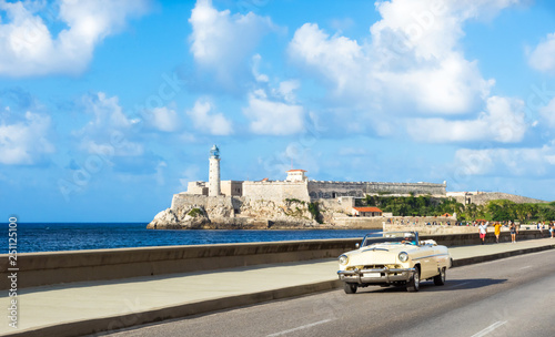 Amerikanischer weisser Cabriolet Oldtimer auf dem berühmten Malecon und im Hintergrund die Festung Castillo de los Tres Reyes del Morro in Havanna Kuba - Serie Kuba Reportage