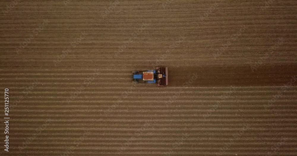 Farmer in tractor preparing land with seedbed cultivator. Agriculture. Tractor plowing field and preparing land for people who plant strawberry. Agronomy farming and husbandry concept. Aerial video.