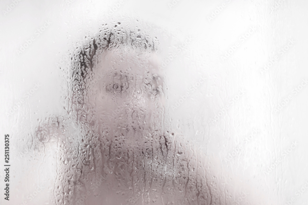 Water drops on the glass of the shower against the girl