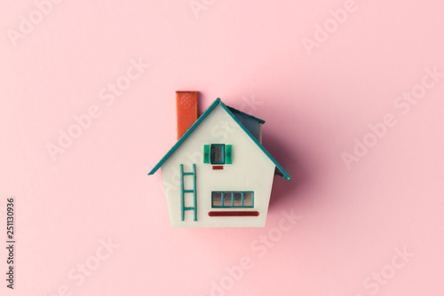 Plastic house model on pink background. Real estate concept