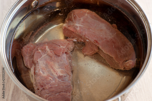 Raw meat in a saucepan with water. Cooking beef dishes. Pulp raw meat cooked in a pan of water.