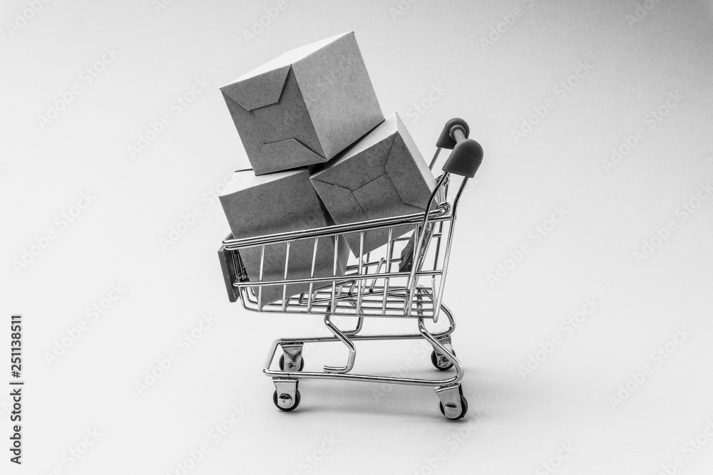 Shopping cart and box on black and white background, business and shopping concept. Selective focus Shopping cart and box on black and white background, business and shopping concept. Selective focus