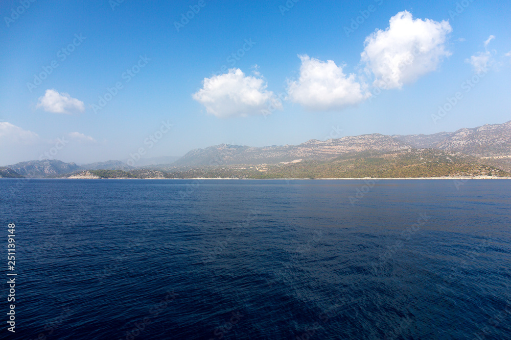 Mediterranean sea overlooking the mountains. Aerial top view of sea waves hitting rocks on the beach with turquoise sea water. Amazing rock cliff seascape in the coastline.