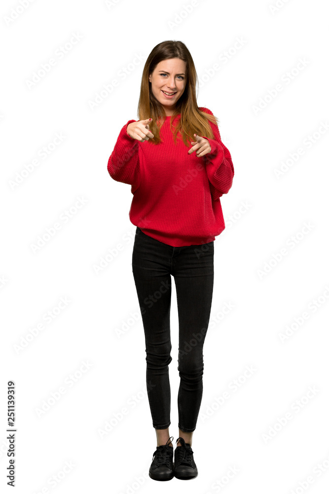 A full-length shot of a Young woman with red sweater pointing to the front and smiling over isolated white background A full-length shot of a Young woman with red sweater pointing to the front and smiling over isolated white background