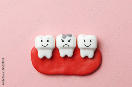 Healthy white teeth are smiling and tooth with caries is sad on pink background.