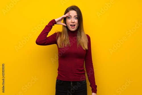 Woman with turtleneck over yellow wall has just realized something and has intending the solution