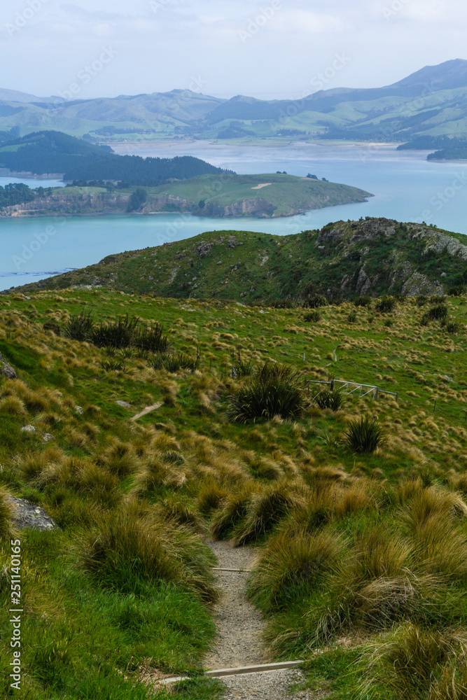 Foot path leading from mountain peak into valley and bay in distance