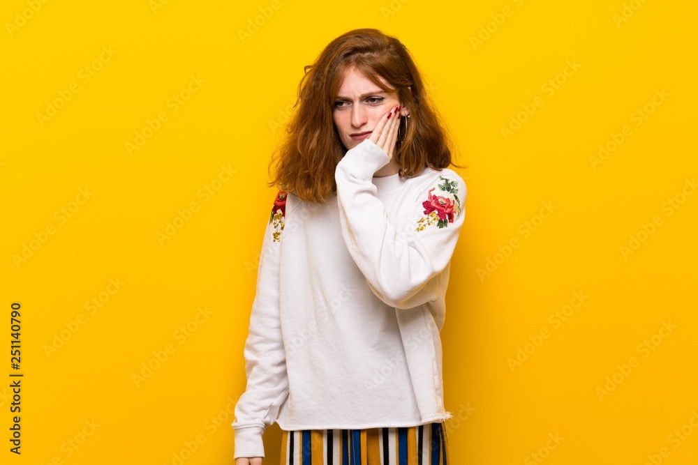 Young redhead woman over yellow wall with toothache Young redhead woman over yellow wall with toothache