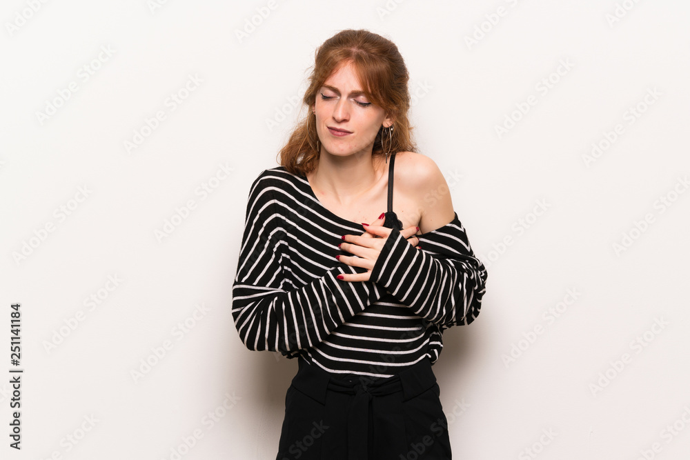 Young redhead woman over white wall having a pain in the heart Young redhead woman over white wall having a pain in the heart