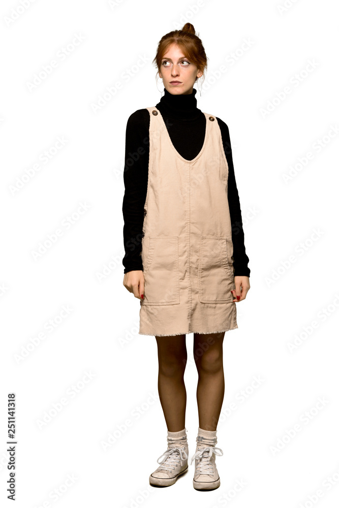 Fototapeta premium A full-length shot of a Young redhead woman looking up with serious face over isolated white background