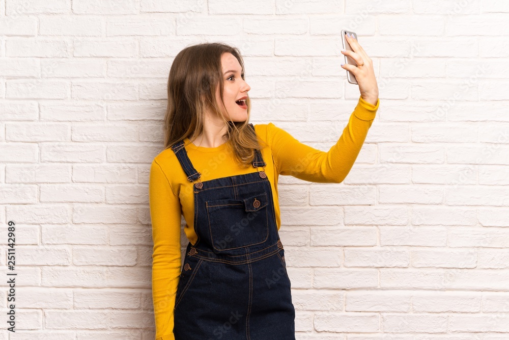 Teenager girl over white brick wall making a selfie Teenager girl over white brick wall making a selfie
