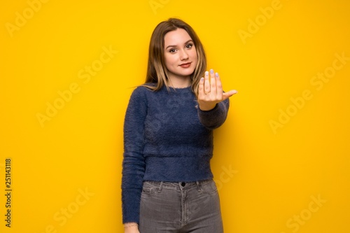 Teenager girl over yellow wall inviting to come with hand. Happy that you came