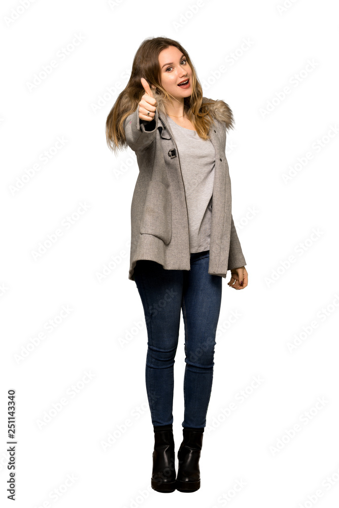 A full-length shot of a Teenager girl with coat giving a thumbs up gesture because something good has happened on isolated white background A full-length shot of a Teenager girl with coat giving a thumbs up gesture because something good has happened on isolated white background