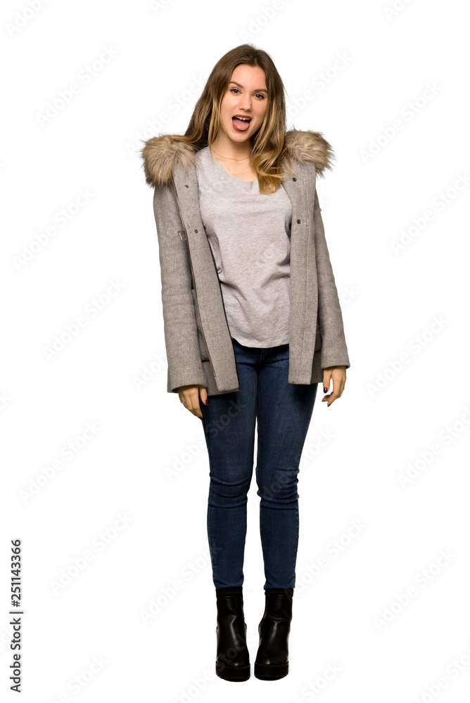 A full-length shot of a Teenager girl with coat showing tongue at the camera having funny look on isolated white background A full-length shot of a Teenager girl with coat showing tongue at the camera having funny look on isolated white background