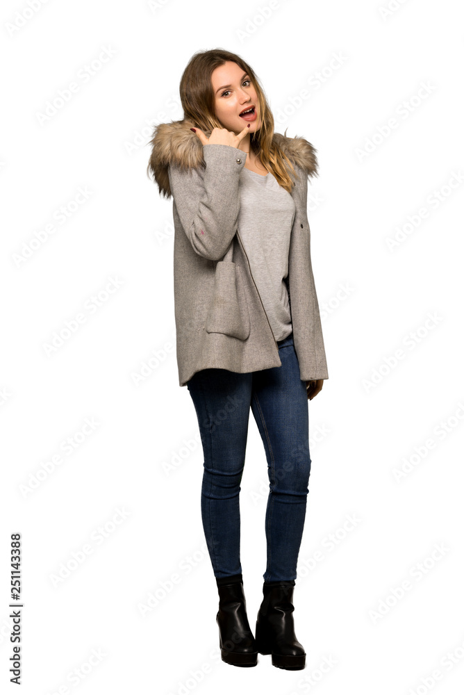 A full-length shot of a Teenager girl with coat making phone gesture. Call me back sign on isolated white background A full-length shot of a Teenager girl with coat making phone gesture. Call me back sign on isolated white background