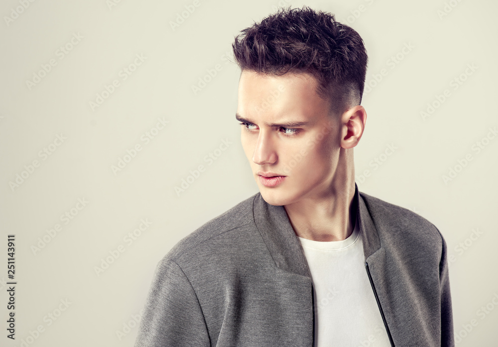 Obraz premium Fashion portrait of a handsome man with a fashionable hair style in a stylish gray jacket.