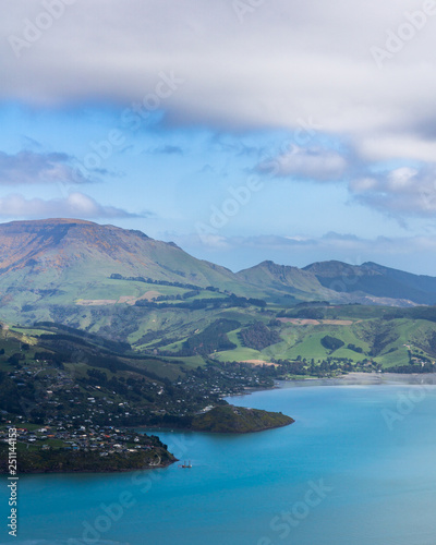 Beautiful blue bay filled with light, green hills covered by shadows