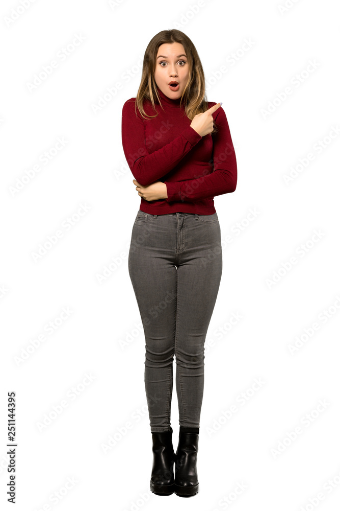 A full-length shot of a Teenager girl with turtleneck surprised and pointing side over isolated white background A full-length shot of a Teenager girl with turtleneck surprised and pointing side over isolated white background
