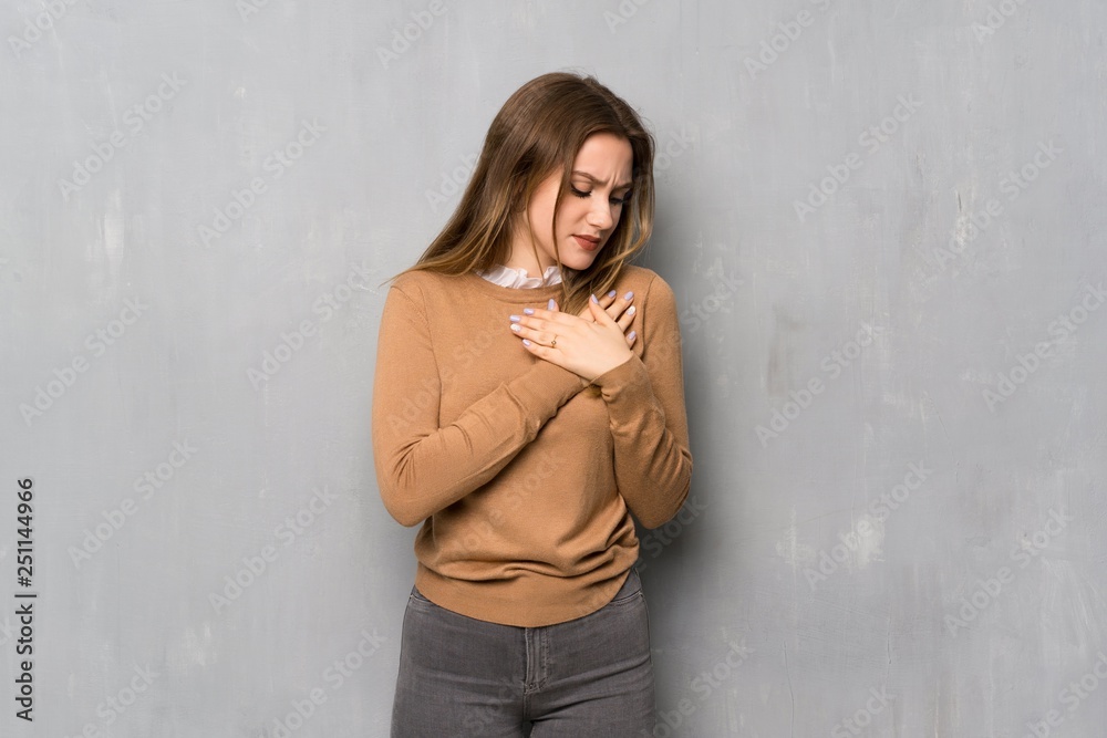 Fototapeta premium Teenager girl over textured wall having a pain in the heart