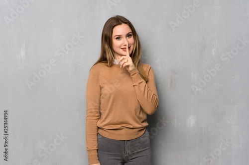 Teenager girl over textured wall showing a sign of silence gesture © luismolinero